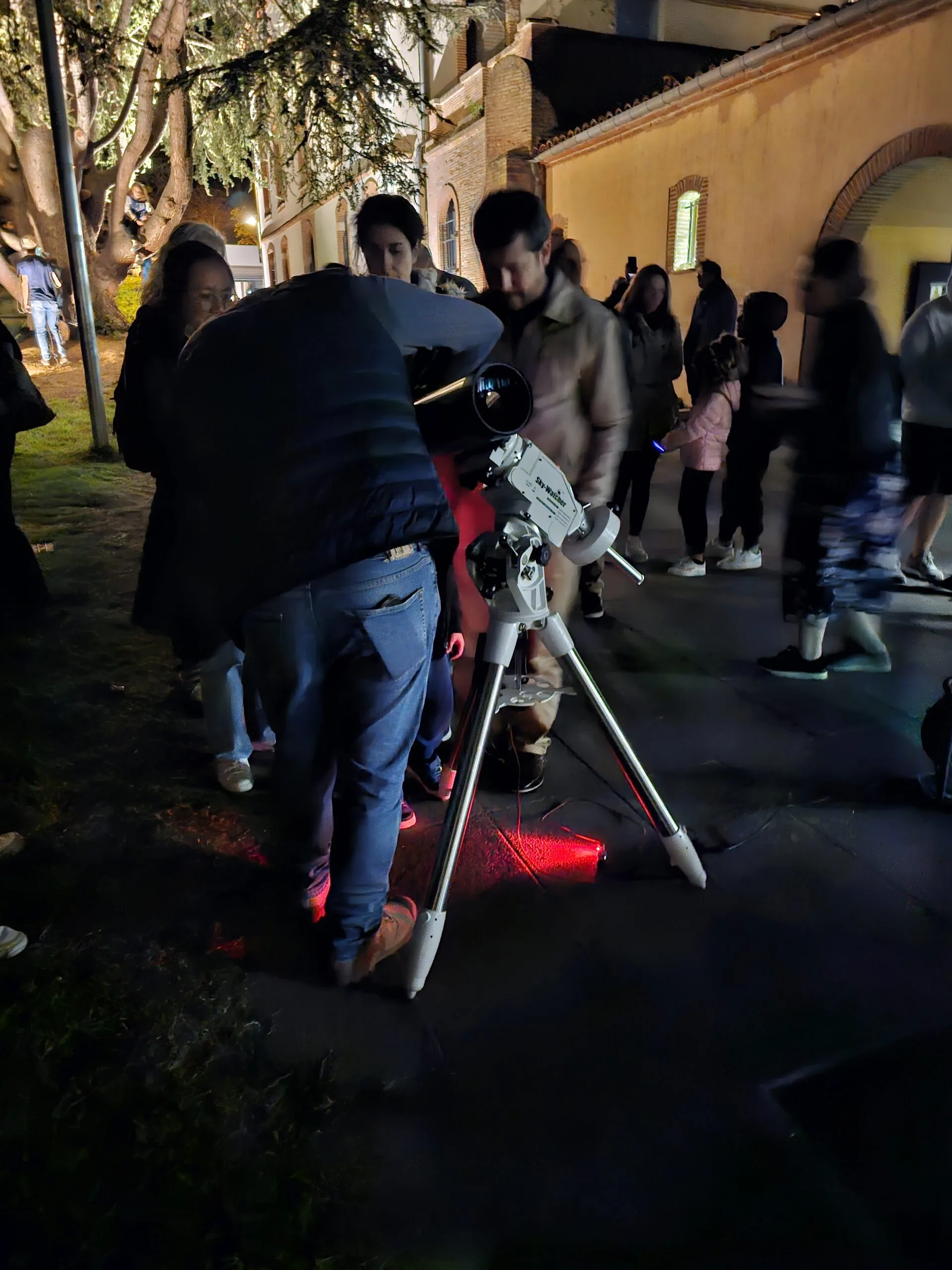 People gathered around a telescope at La Tête dans les Étoiles in Ayguesvives