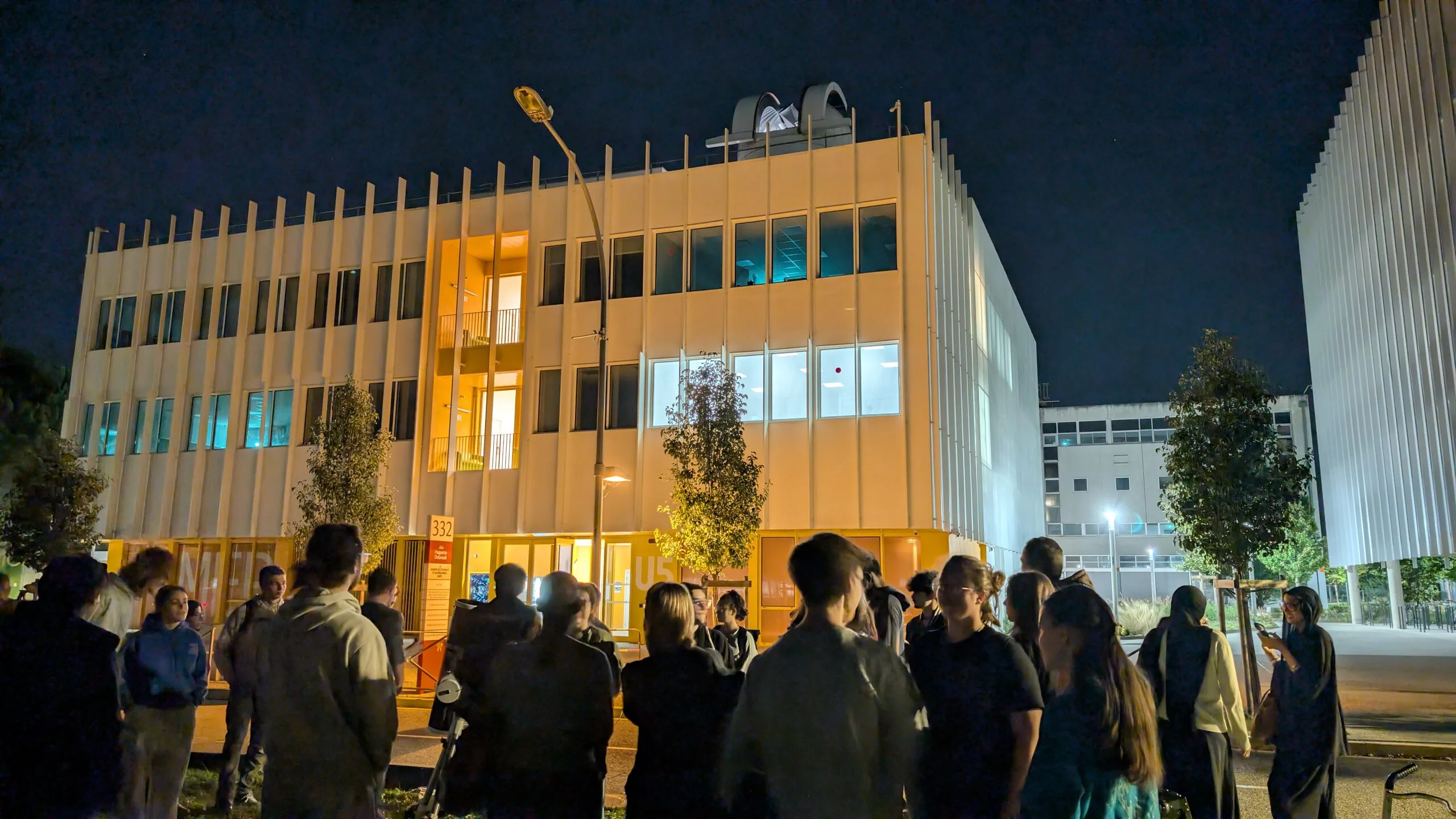 A night-time gathering in front of the lit observatory building